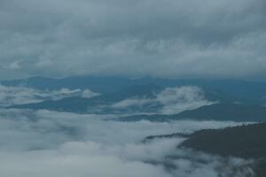 Mountain range with visible silhouettes through the morning blue fog. photo