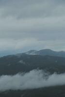 Mountain range with visible silhouettes through the morning blue fog. photo