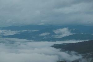 Mountain range with visible silhouettes through the morning blue fog. photo