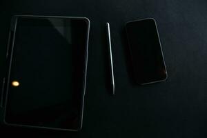 Open laptop with digital tablet and white smartphone. All with isolated screen on old wooden desk. photo