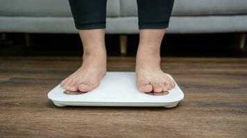 Fat diet and scale feet standing on electronic scales for weight control. Measurement instrument in kilogram for a diet control. photo