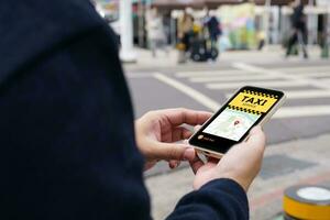 Man in downtown city street ordering taxi using smart phone app Booking taxi using application online on smart phone photo