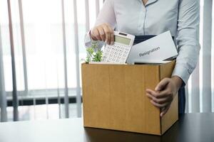 Business woman sending resignation letter and packing Stuff Resign Depress or carrying business cardboard box by desk in office. Change of job or fired from company. photo