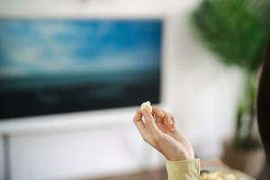 Asian woman Watching smart TV and using remote controller Hand holding television audio remote control at home with the remote control television photo