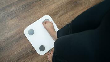 feet standing on electronic scales for weight control. Measurement instrument in kilogram for a diet control photo