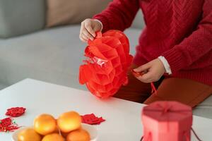 Asian Woman holding red Chinese new year lantern while decorated flat putting traditional pendant to the Chinese New Year Celebrations for good luck. chinese word means blessing photo