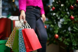 contento asiático niña sostener compras pantalones Navidad presente. alegre mujer con Navidad nuevo año invierno rebaja foto