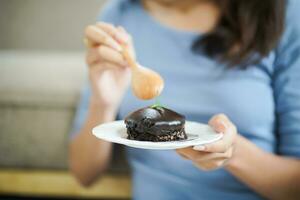 Beautiful Asian woman eating tasty chocolate cake. Teen girl eating the cake. photo