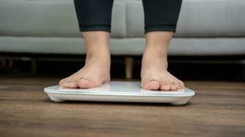 Fat diet and scale feet standing on electronic scales for weight control. Measurement instrument in kilogram for a diet control. photo