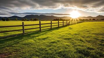 Green grass field, wooden Fence and mountain on horizon at summer morning. American spring sunrise. Generative AI photo