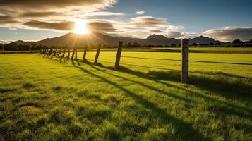 Green grass field, wooden Fence and mountain on horizon at summer morning. American spring sunrise. Generative AI photo