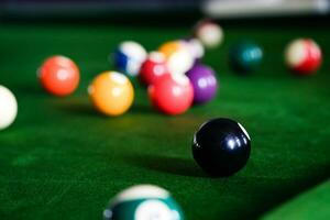 Man's hand and Cue arm playing snooker game or preparing aiming to shoot pool balls on a green billiard table. Colorful snooker balls on green frieze. photo