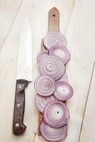 a knife and a bunch of onions on a cutting board photo