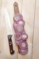 a knife and a bunch of onions on a cutting board photo