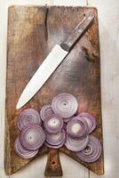 a knife and a bunch of onions on a cutting board photo