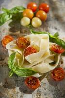 Nest of pasta with basil and tomato photo