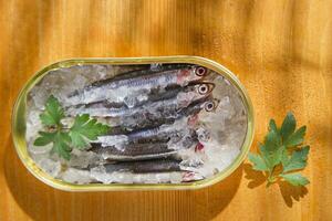 fresh herring in a tin on a wooden table photo