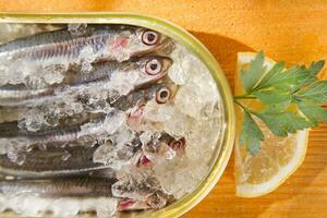 fresh herring in a tin on a wooden table photo