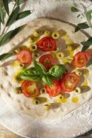 Raw pizza with tomato and olives photo