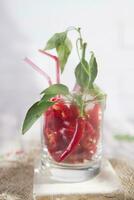a glass filled with red peppers and a straw photo