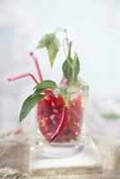 a glass filled with red peppers and a straw photo