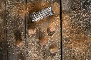 a grater with nuts on a wooden surface photo