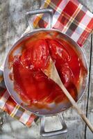 a pan with tomatoes and a wooden spoon photo