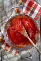 a pan with tomatoes and a wooden spoon photo