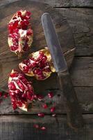 a knife and a pomegranate on a wooden cutting board photo