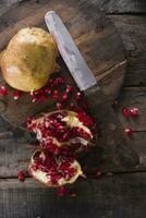 a knife and a pomegranate on a wooden cutting board photo