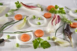 un blanco mesa con zanahorias, cebollas, apio y perejil foto