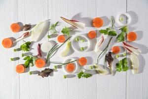 a white wooden table with carrots, celery and herbs photo