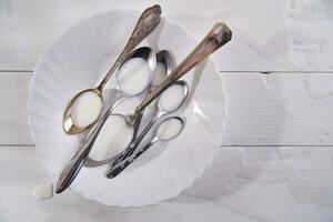 two spoons on a white plate with milk photo