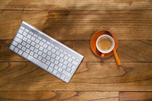 a keyboard, mouse and coffee cup on a wooden table photo