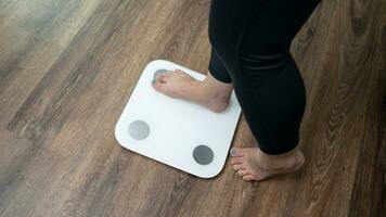 pies en pie en electrónico escamas para peso control. medición instrumento en kilogramo para un dieta controlar foto