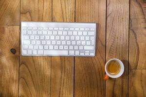 a keyboard, mouse and coffee cup on a wooden table photo