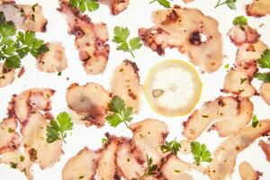 a plate of sliced octopus with lemon slices photo