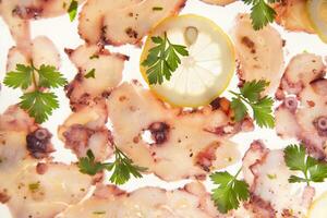 a plate of sliced octopus with lemon slices photo