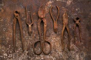 un grupo de oxidado antiguo herramientas sentado en un pared foto