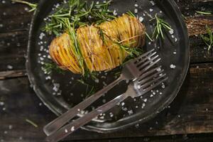 a pile of potatoes with herbs and spices on a wooden table photo