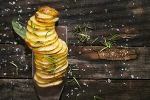 a knife and a bunch of sliced potatoes on a wooden table photo