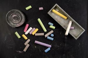 a pile of colored chalk sticks on a black table photo