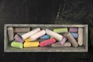 a pile of colored chalk sticks on a black table photo