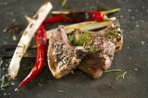 grilled lamb chops with herbs and spices on a black slate photo