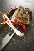 grilled lamb chops with herbs and spices on a black slate photo