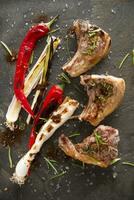 grilled lamb chops with herbs and spices on a black slate photo