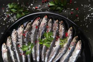 Fresco sardinas en un negro plato con hierbas foto