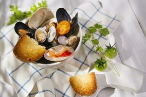 a bowl of mussels and bread on a white table photo