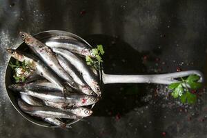 fresh sardines in a black dish with herbs photo