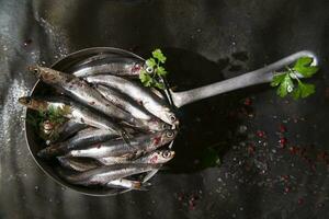 Fresco sardinas en un negro plato con hierbas foto